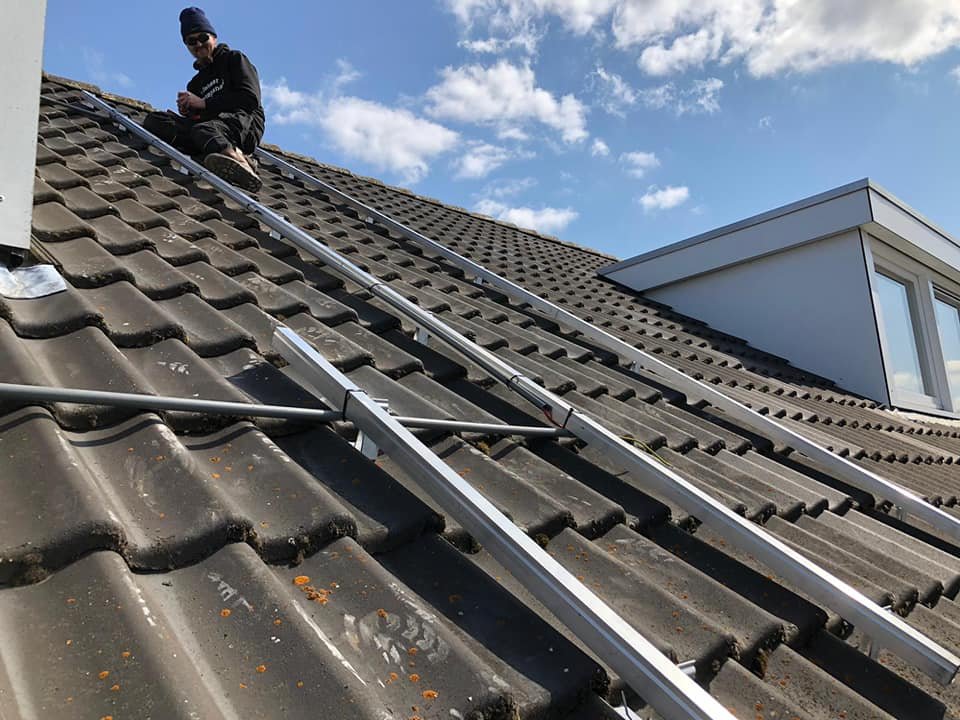Monteur legt aluminium montagerails aan op een donker pannendak