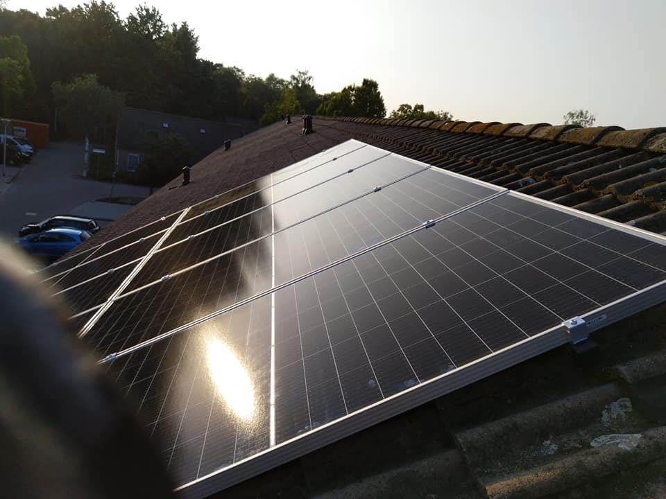Zonnepanelen op een schuin dak met de laagstaande zon erop
