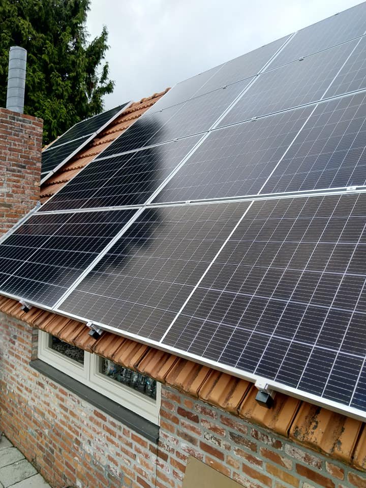 Zonnepanelen op het dak van een schuur met rode bakstenen gevel