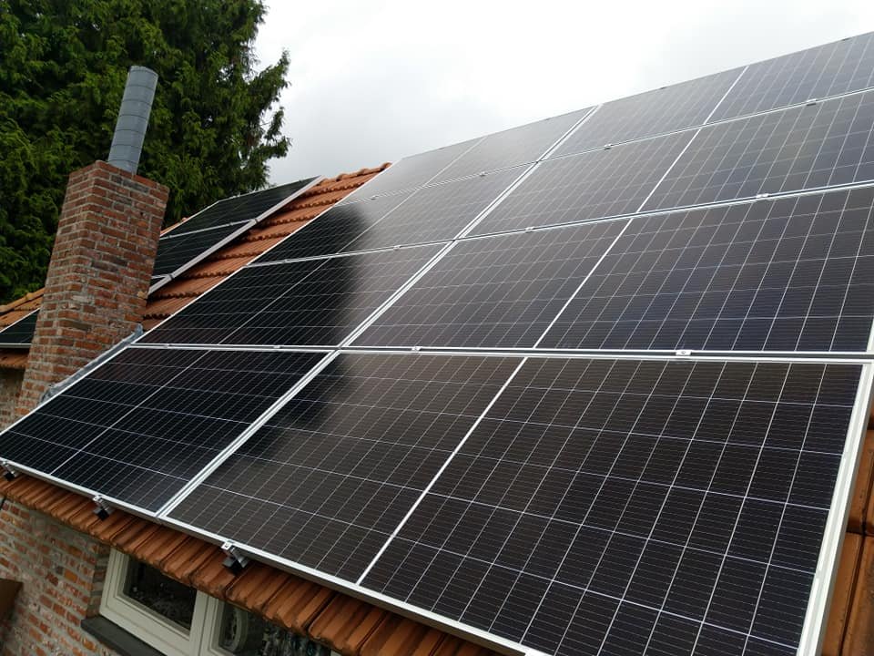Volledig belegd schuurdak met zonnepanelen naast een schoorsteen